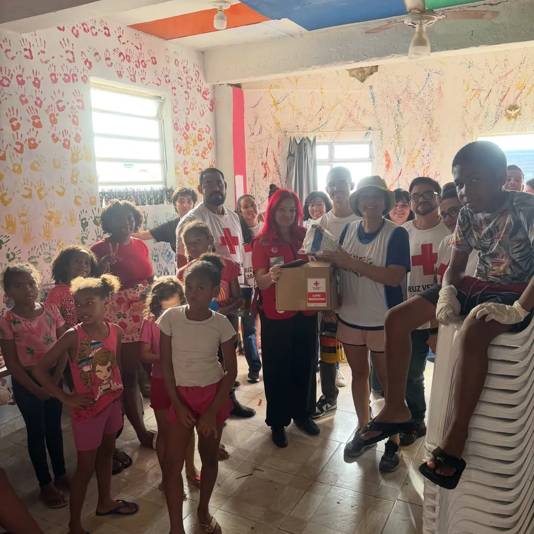 Voluntários da Cruz Vermelha e crianças reunidos durante uma ação comunitária.